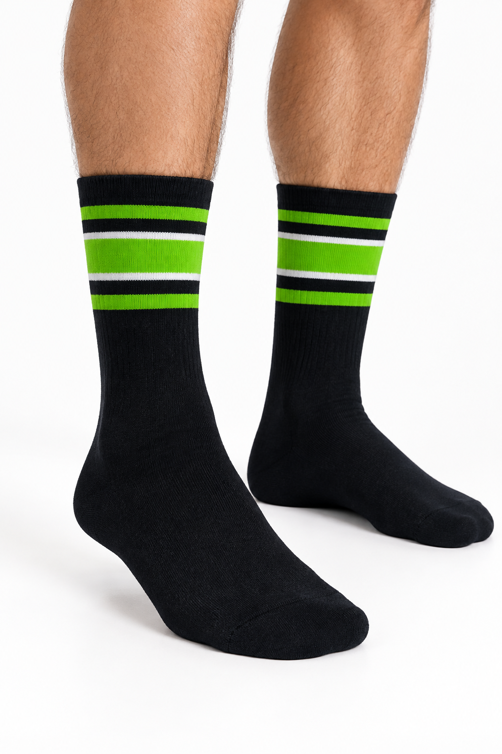 Male model’s lower legs wearing black socks with lime green and white stripes in a white studio